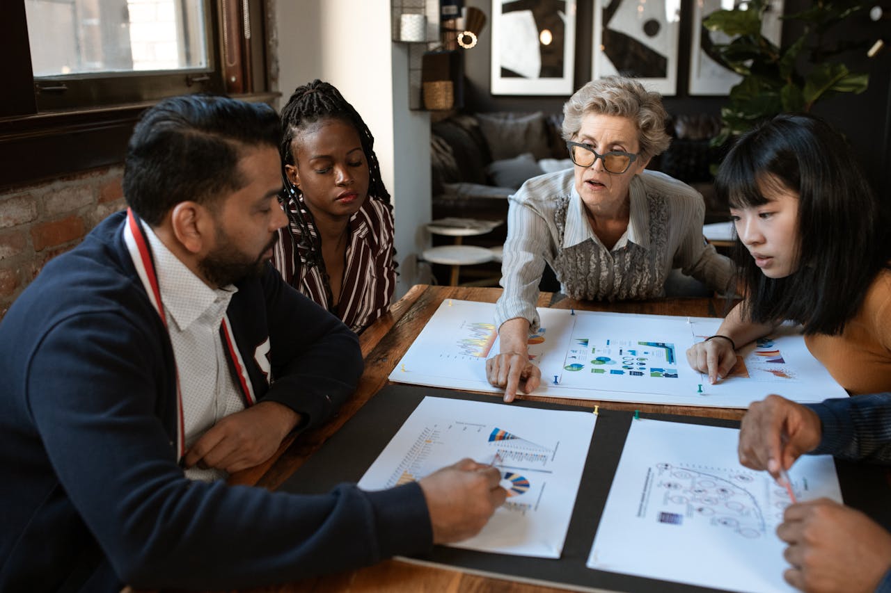 A diverse group of professionals brainstorming over charts in a stylish office setting.